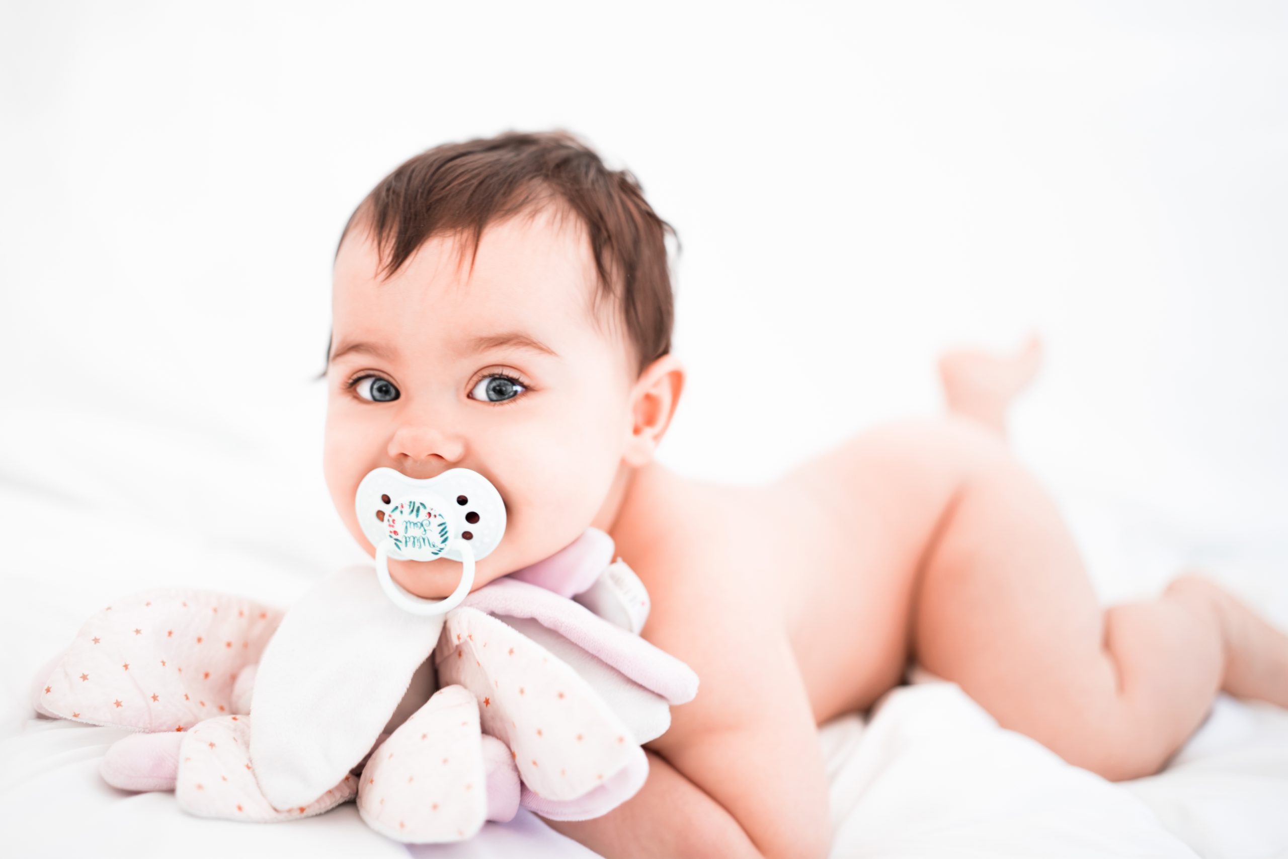 Photographe bébé avec doudou et tétine beau regard yeux bleus par photographe Le Mans en Sarthe